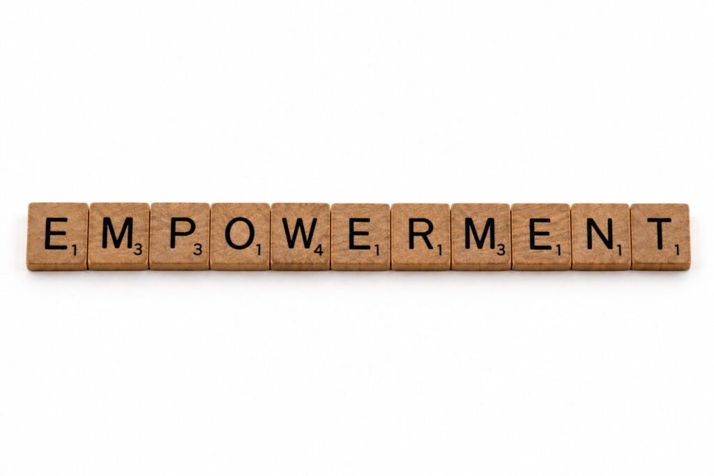 Fa Scrabble-kockákból kirakott EMPOWERMENT szó, a felhatalmazás és a munkatársak megerősítésének témáját szimbolizálva