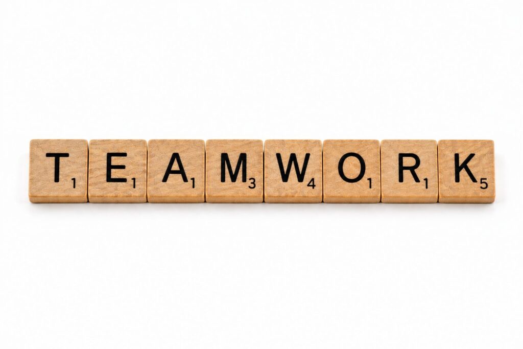 Fa Scrabble-kockákból kirakott TEAMWORK szó, a csapatmunka témáját szimbolizálva