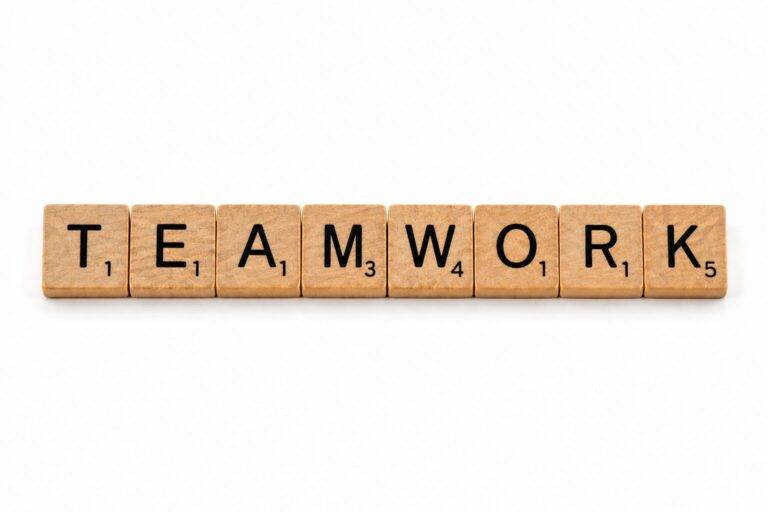 Fa Scrabble-kockákból kirakott TEAMWORK szó, a csapatmunka témáját szimbolizálva