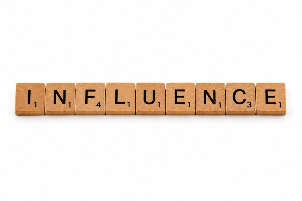 Fa Scrabble-kockákból kirakott INFLUENCE szó, a befolyás és a meggyőzés építésének témáját szimbolizálva